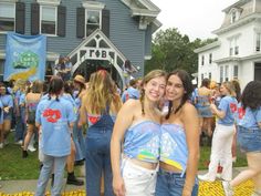 two young women standing next to each other in front of a crowd of people wearing blue shirts