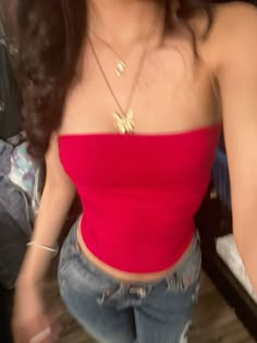 a woman in jeans and a red top taking a selfie