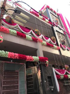 the building is decorated with pink and white flowers on it's side, along with other decorations