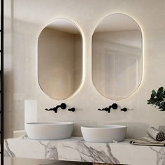 two round mirrors are mounted on the wall above sinks in a bathroom with marble counter tops