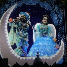 two people dressed in costumes standing on a stage with a large screen behind them that has an image of a man and woman sitting on the moon