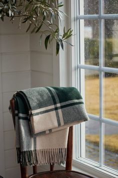 a blanket sitting on top of a wooden chair next to a window