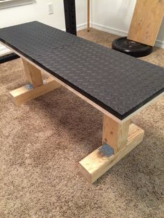 a wooden bench sitting on top of a carpeted floor next to a black table