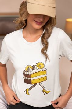 Step into the whimsical world of fashion with our quirky Lemon Cake Walking T-Shirt! This unisex tee features a delightful graphic of a lemon cake slice strutting in high heels, making it the perfect gift for dessert lovers and anyone with a sweet tooth. Crafted from high-quality fabric, this comfortable and stylish shirt is great for casual outings, parties, or as a unique novelty gift. Embrace the fun side of fashion and let your personality shine with this charming and humorous design. We uti Sweet Cartoon Print Crew Neck T-shirt, Sweet Style Crew Neck T-shirt With Cartoon Print, Sweet White T-shirt With Graphic Print, Sweet White T-shirt With Funny Print, White Sweet T-shirt With Funny Print, Heels Unique, Cake Walk, Novelty Shirts, Dessert Lover