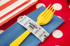 yellow forks and spoons are sitting on a blue napkin with red polka dot tablecloth