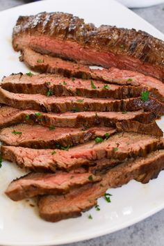 sliced steak on a plate with parsley garnish and seasoning sprig