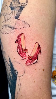 a woman's arm with a tattoo on it that has two red shoes in the air