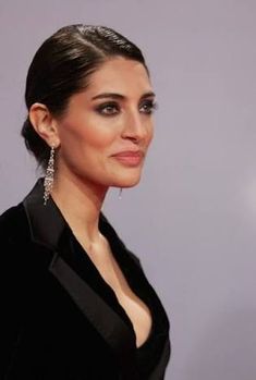 a woman in a black dress with earrings on her head and dark eyeshadow