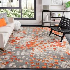 an orange and gray rug in a living room with a couch, chair and window