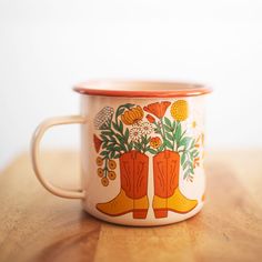 an orange and white coffee cup sitting on top of a wooden table