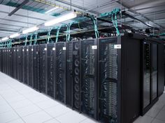 rows of servers in a data center with wires hanging from the ceiling and on top of them