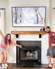 a man and woman standing in front of a fire place with their arms out to the side