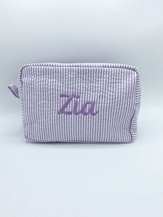 a purple and white striped cosmetic bag with the word'zia'on it