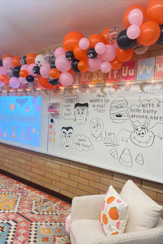 balloons are hanging from the ceiling in front of a whiteboard with writing on it