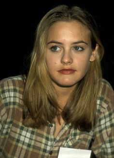 a young woman sitting at a table with a name tag on it's chest