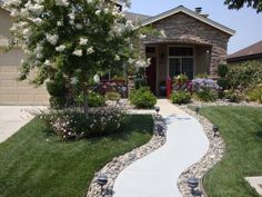 a house with landscaping in front of it and flowers growing on the side of the driveway