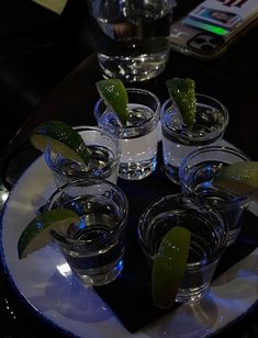 several shot glasses with lime wedges in them