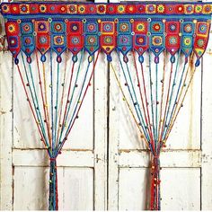 the curtains are decorated with colorful beads and tassels, hanging on an old white door