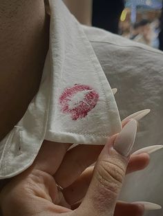 a woman's hand holding onto a white cloth with red lipstick imprint on it