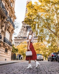 a woman walking down the street in front of the eiffel tower