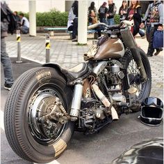 a motorcycle that is parked on the side of the road with people standing around it