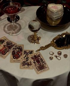 a table topped with lots of cards next to a cake and wine glass on top of it