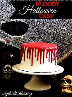 a halloween cake with white icing and red drizzle on top, next to a bottle of booze