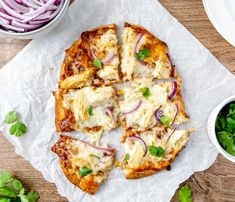 a pizza sitting on top of a piece of paper next to a bowl of salad