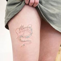 a woman's thigh with a tattoo on her left leg and a dragon drawn on it