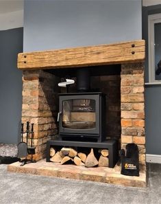 a wood burning stove sitting inside of a living room next to a pile of logs