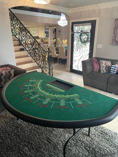 a green table sitting in the middle of a living room next to a stair case