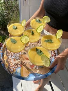 a person holding a platter with drinks and lime wedges on it, in front of a door