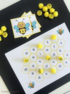 a bee themed counting game with yellow pom poms on the table next to it