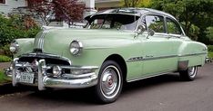 an old green car parked in front of a house