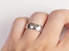 a person's hand with a silver ring on top of their finger and white background