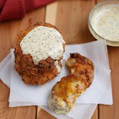 two fried food items sitting on top of a white napkin next to a cup of sauce