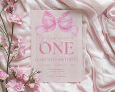 a pink birthday card with a bow on the front and one in the middle, surrounded by pink flowers