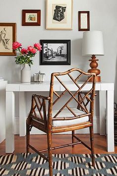 a chair sitting in front of a white table with flowers on it and a lamp