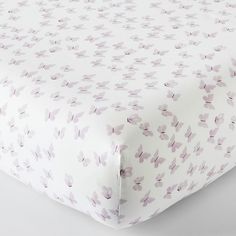 a close up of a bed sheet with purple flowers on the cover and white sheets