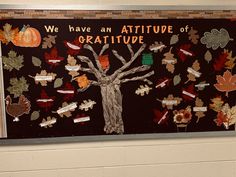 a bulletin board with fall leaves and a tree in the center that says we have an attitude of gratitude