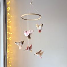 a group of birds that are hanging from a string on a wall next to a window