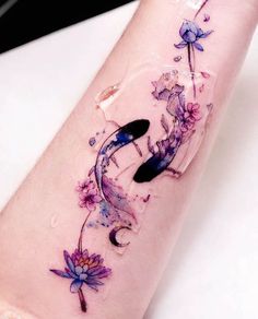 a woman's arm with watercolor tattoos on it