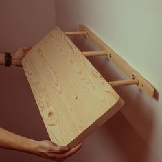 two hands are holding a wooden shelf that is made out of plywood planks