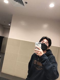 a man taking a selfie in front of a mirror wearing a black hoodie