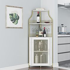 a white cabinet with wine glasses and bottles in it next to a wall mounted painting