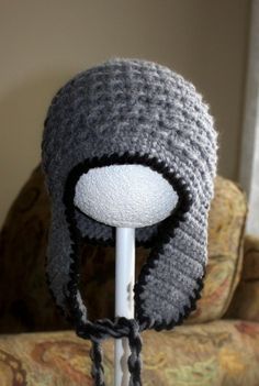 a crocheted hat is on top of a white pole in front of a couch