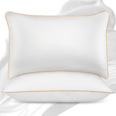 two white pillows with gold piping on them