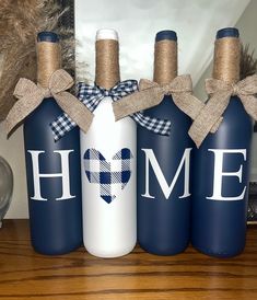 three wine bottles with the word home painted on them