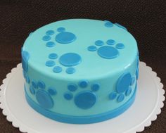 a cake with blue icing and paw prints on it sitting on a white plate