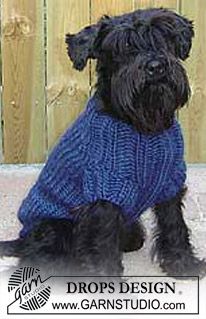 a black dog wearing a blue sweater sitting in front of a wooden fence with the words drops design on it